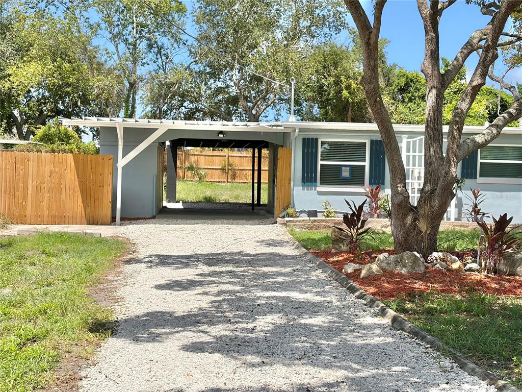 A gravel driveway leads to a covered carport attached to the side of a house — 12119 VICTORY DRIVE, HUDSON, FL