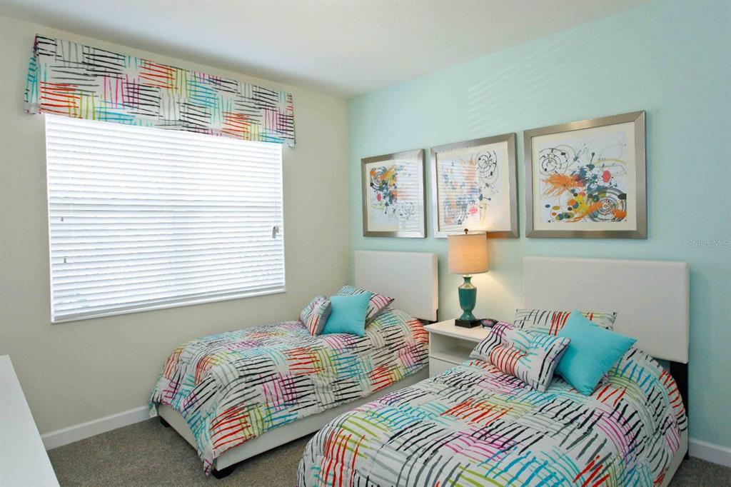 A bedroom features two twin beds with colorful patterned bedding and a shared nightstand — 4839 KINGS CASTLE CIRCLE, KISSIMMEE, FL