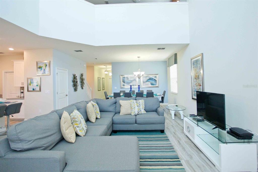 A living room with a large gray sectional sofa, a television, and a dining area — 4839 KINGS CASTLE CIRCLE, KISSIMMEE, FL