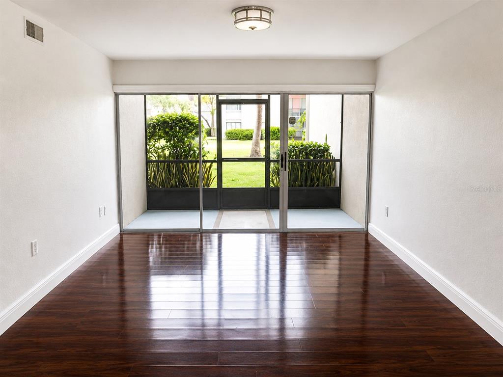 A room with dark wood flooring, white walls, and a sliding glass door to a patio — 3236 S SEMORAN BOULEVARD UNIT 15, ORLANDO, FL