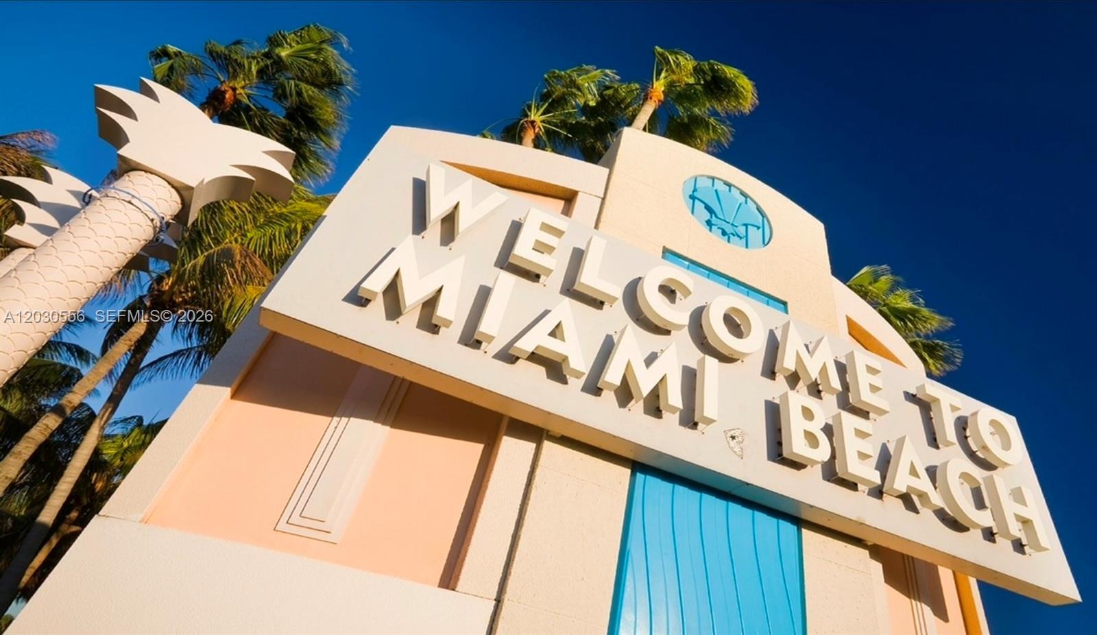 A low-angle view of a Welcome to Miami Beach sign with palm trees against blue sky — 711 Lenox Ave, Miami Beach FL 33139, MIAMI BEACH, FL