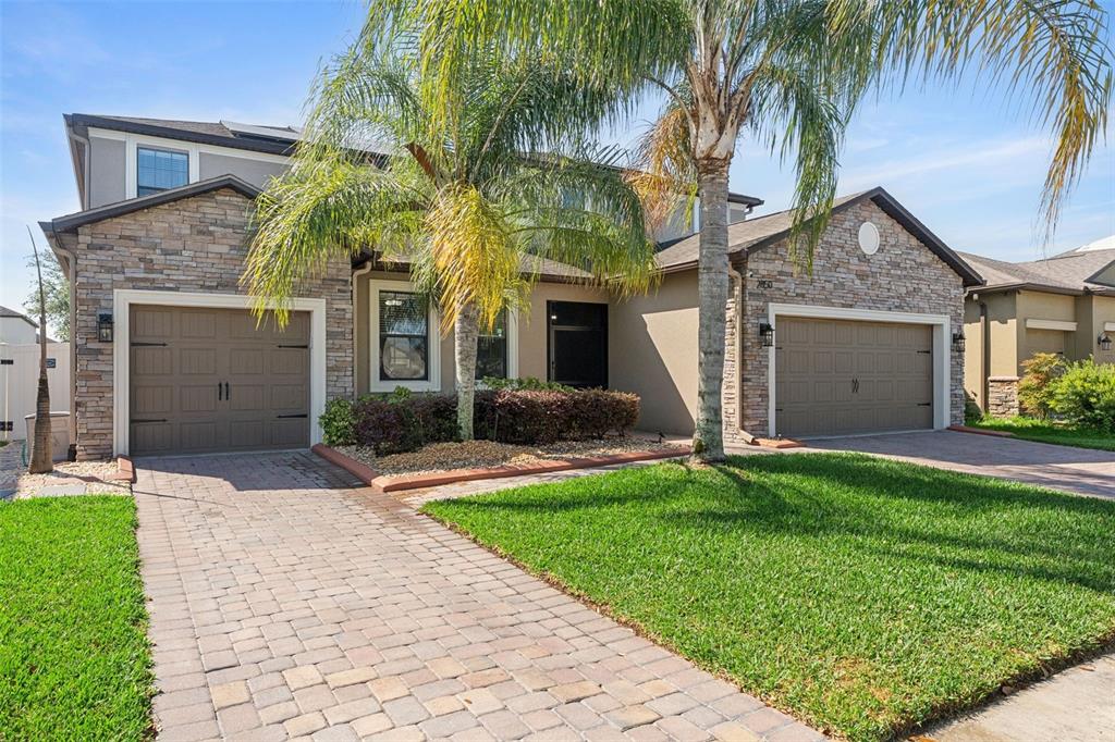 A two-story house with stone veneer, two garage doors, and a paved driveway — 2850 SPRING BREEZE WAY, KISSIMMEE, FL