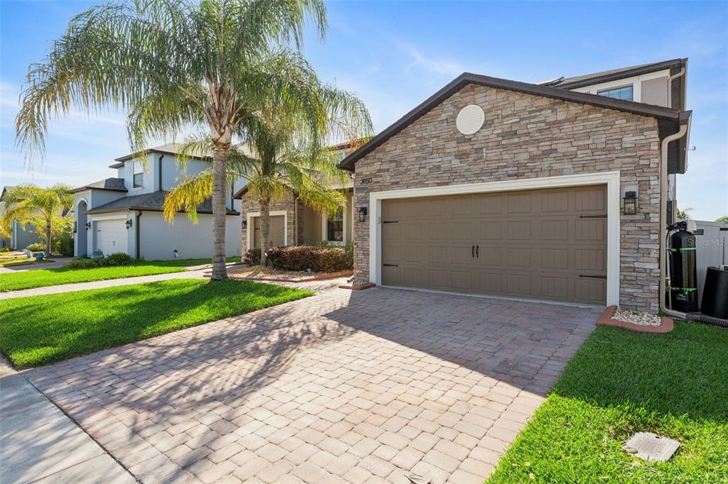 A suburban house with a stone facade, a two-car garage, and a paved driveway — 2850 SPRING BREEZE WAY, KISSIMMEE, FL