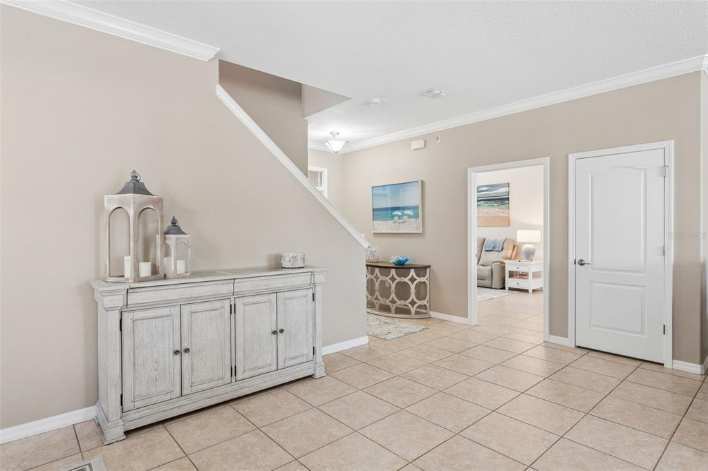 A tiled entryway features a white wooden sideboard, a staircase, and a doorway to another room — 2850 SPRING BREEZE WAY, KISSIMMEE, FL