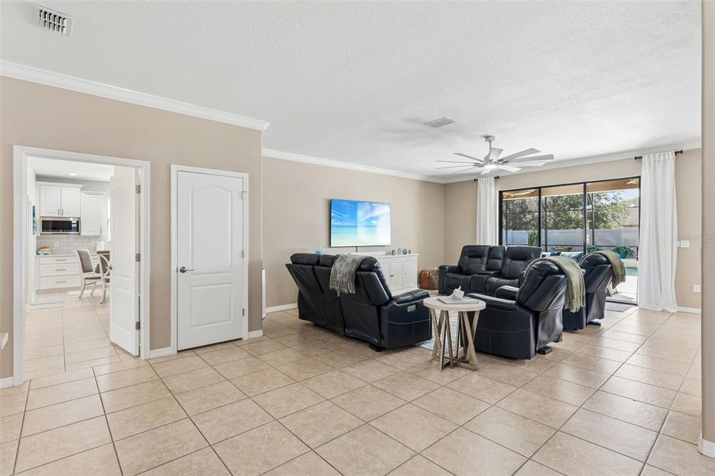 A living room with tile floors, black leather recliners, and a view of a pool — 2850 SPRING BREEZE WAY, KISSIMMEE, FL