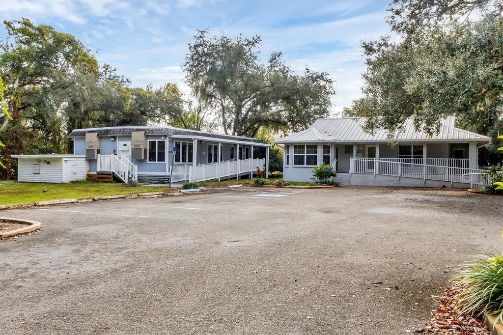 Two light-colored buildings with wheelchair ramps sit behind a large, unpaved parking lot — 37220 GLENWOOD AVENUE, MYAKKA CITY, FL