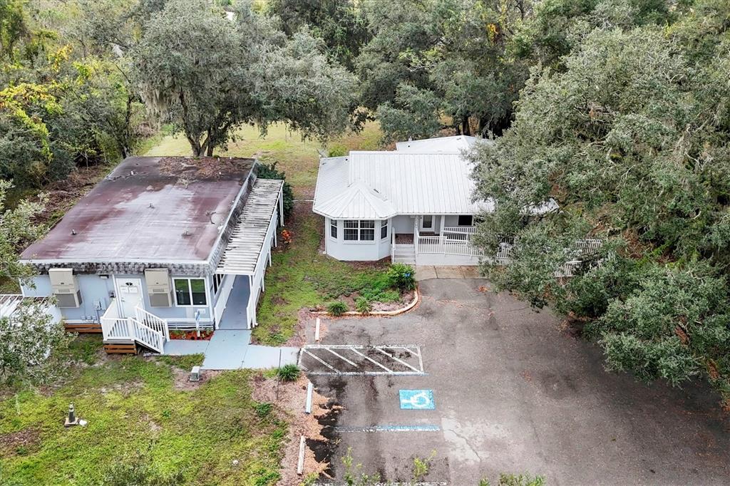 An aerial view shows two buildings with metal roofs situated on a paved parking lot — 37220 GLENWOOD AVENUE, MYAKKA CITY, FL