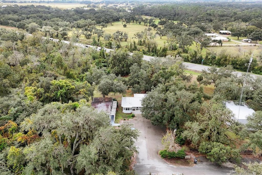 An aerial view shows a white building with a metal roof surrounded by dense trees — 37220 GLENWOOD AVENUE, MYAKKA CITY, FL