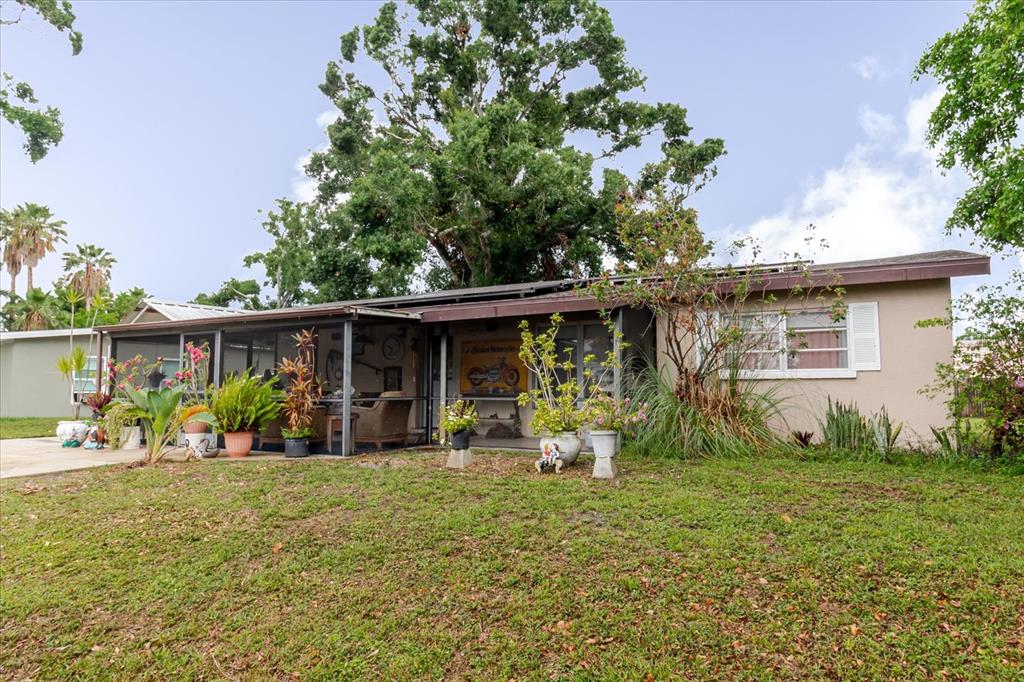 A single-story house with a screened-in porch and a large tree in the front yard — 4015 ASBURY PLACE, SARASOTA, FL