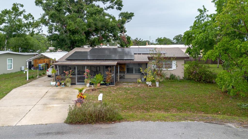 A single-story house with a solar panel roof, a screened-in porch, and a concrete driveway — 4015 ASBURY PLACE, SARASOTA, FL