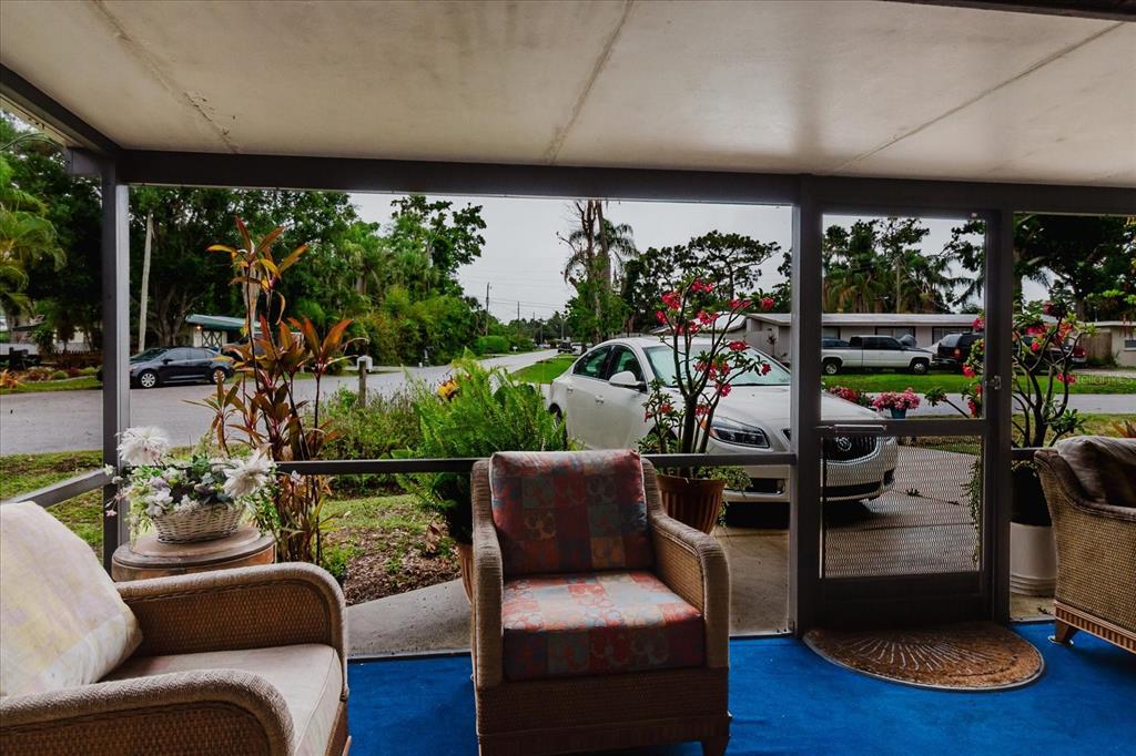 A screened-in porch with wicker furniture overlooks a residential street with parked cars — 4015 ASBURY PLACE, SARASOTA, FL
