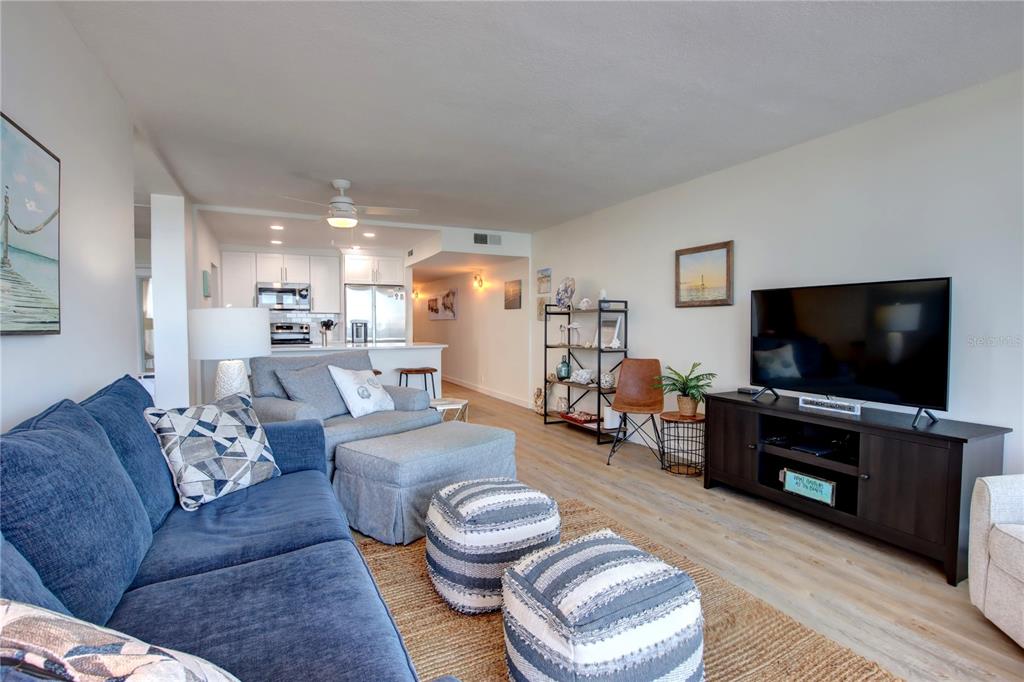 A living room with a blue sofa, gray ottoman, and television on a dark console — 5203 S ATLANTIC AVENUE UNIT 815B, NEW SMYRNA BEACH, FL