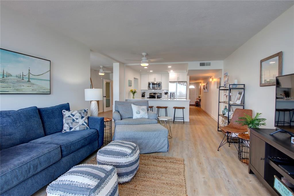 A living room with a blue sofa, gray armchair, and open kitchen with a breakfast bar — 5203 S ATLANTIC AVENUE UNIT 815B, NEW SMYRNA BEACH, FL