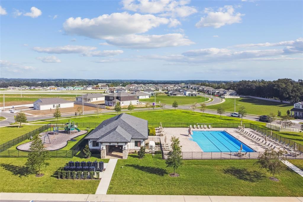 An aerial view shows a community clubhouse with a swimming pool and a playground — 12290 STIRRUP DRIVE, DADE CITY, FL