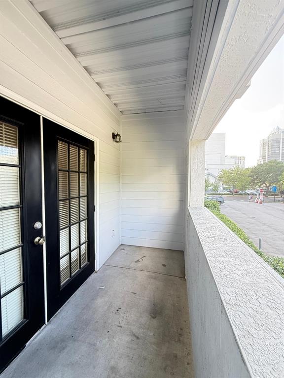 A covered balcony with white horizontal siding, a concrete floor, and black-framed glass doors — 202 E SOUTH STREET UNIT 2038, ORLANDO, FL
