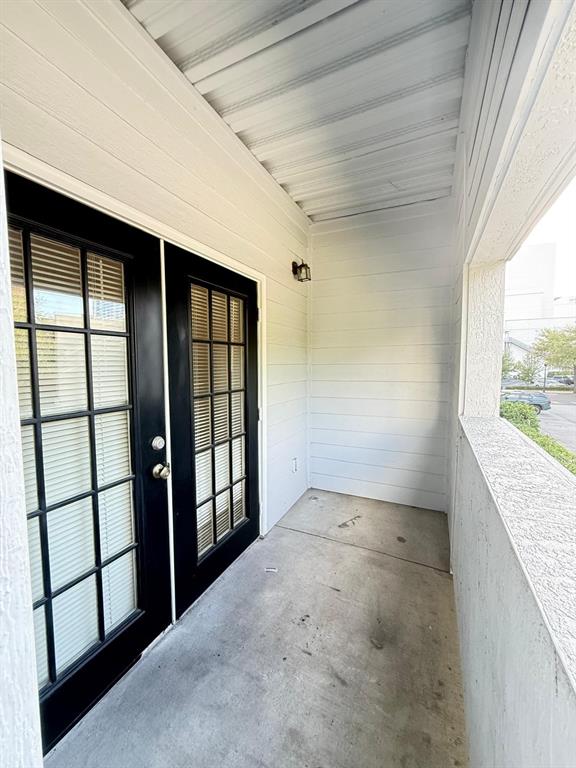A covered balcony features white horizontal siding, a concrete floor, and black French doors — 202 E SOUTH STREET UNIT 2038, ORLANDO, FL