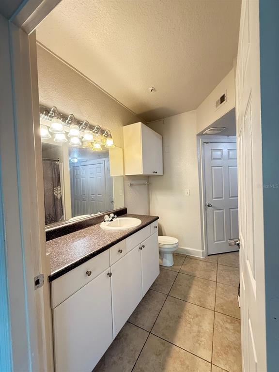 A bathroom features a white vanity with a dark countertop, a mirror, and a toilet — 202 E SOUTH STREET UNIT 2038, ORLANDO, FL