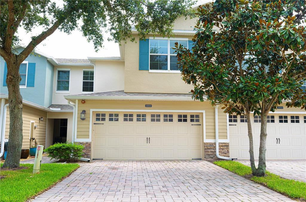 A two-story townhouse with a beige stucco exterior, blue shutters, and a two-car garage — 15510 CAMPDEN STREET, WINTER GARDEN, FL