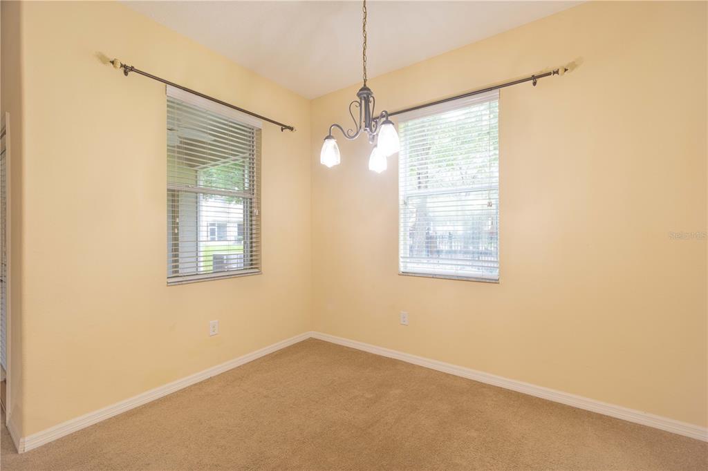 A dining area with beige walls, tan carpeting, a chandelier, and two windows with blinds — 15510 CAMPDEN STREET, WINTER GARDEN, FL