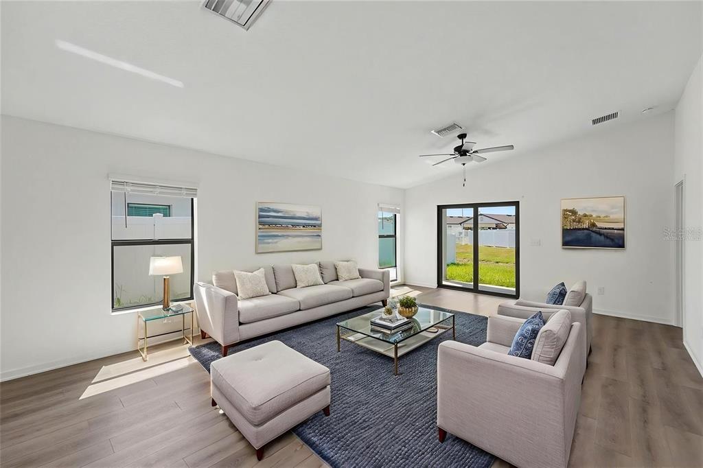 A living room features light-colored furniture, a blue area rug, and sliding glass patio doors — 5669 FLOTILLA AVENUE, TAMPA, FL