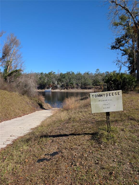 A concrete boat ramp leads into a river next to a sign for Tommy Deese — NW FOX RUN TRAIL UNIT 107, MAYO, FL