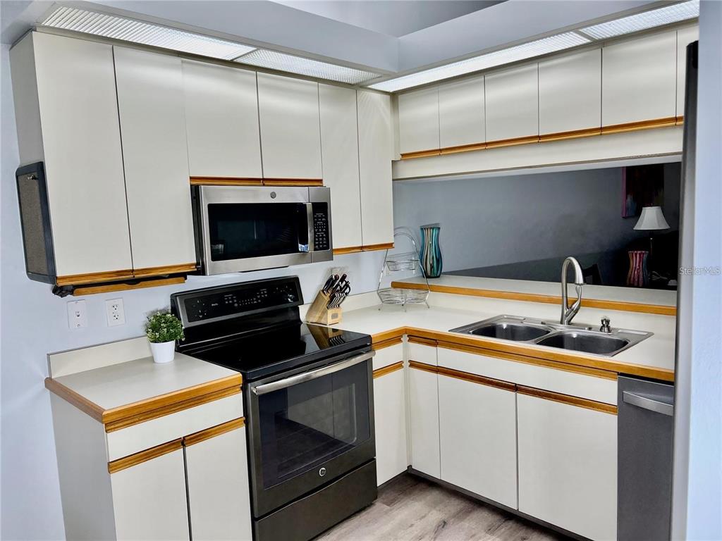 A kitchen features white cabinets with wood trim, black appliances, and a double-basin sink — 7186 LAKESIDE DRIVE, SARASOTA, FL