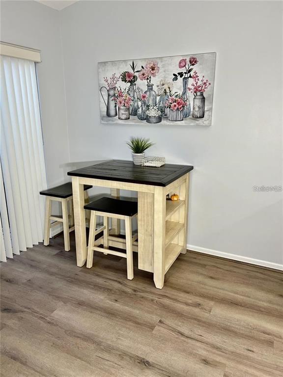 A small dining area features a two-tone pub table with stools and wall art — 7186 LAKESIDE DRIVE, SARASOTA, FL