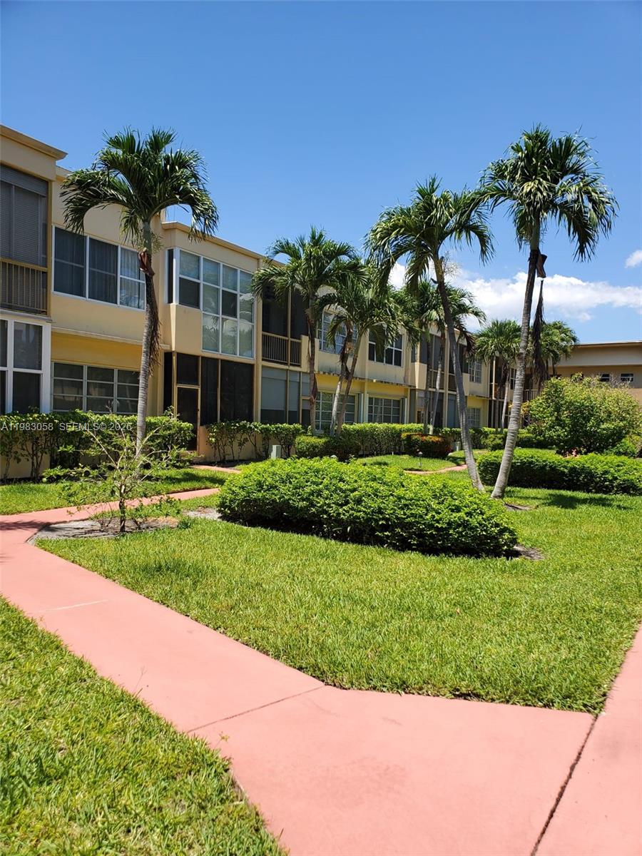 A multi-story apartment building exterior features palm trees and a landscaped lawn with walkways — 851 NE 14th Ave # 414, Hallandale Beach FL 33009, HALLANDALE BEACH, FL