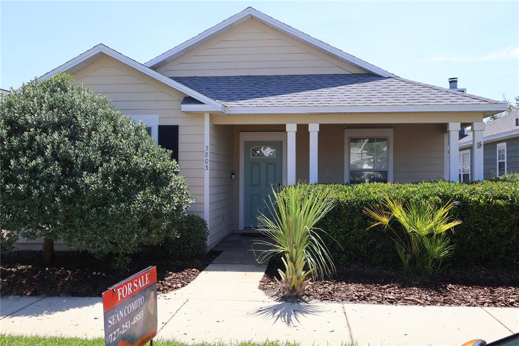 A single-story house with beige siding, a front porch, and a teal front door — 3803 NW 26TH STREET, GAINESVILLE, FL