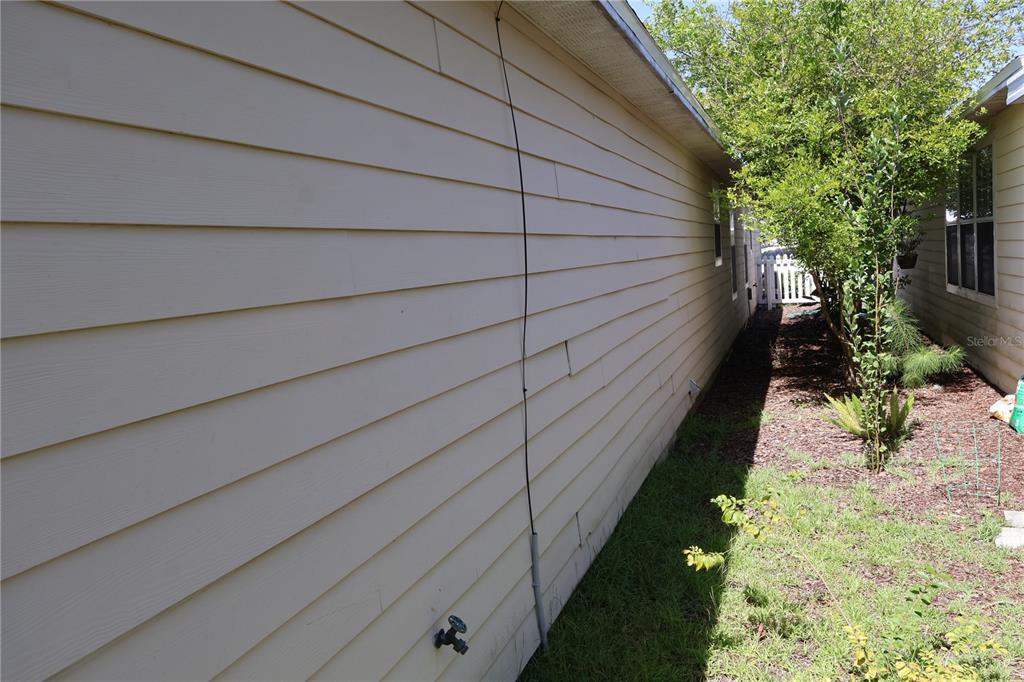 The side exterior of a house features light-colored horizontal siding and a water spigot — 3803 NW 26TH STREET, GAINESVILLE, FL