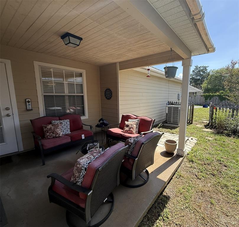 A covered patio features outdoor furniture, a window, and a view of the backyard — 3803 NW 26TH STREET, GAINESVILLE, FL