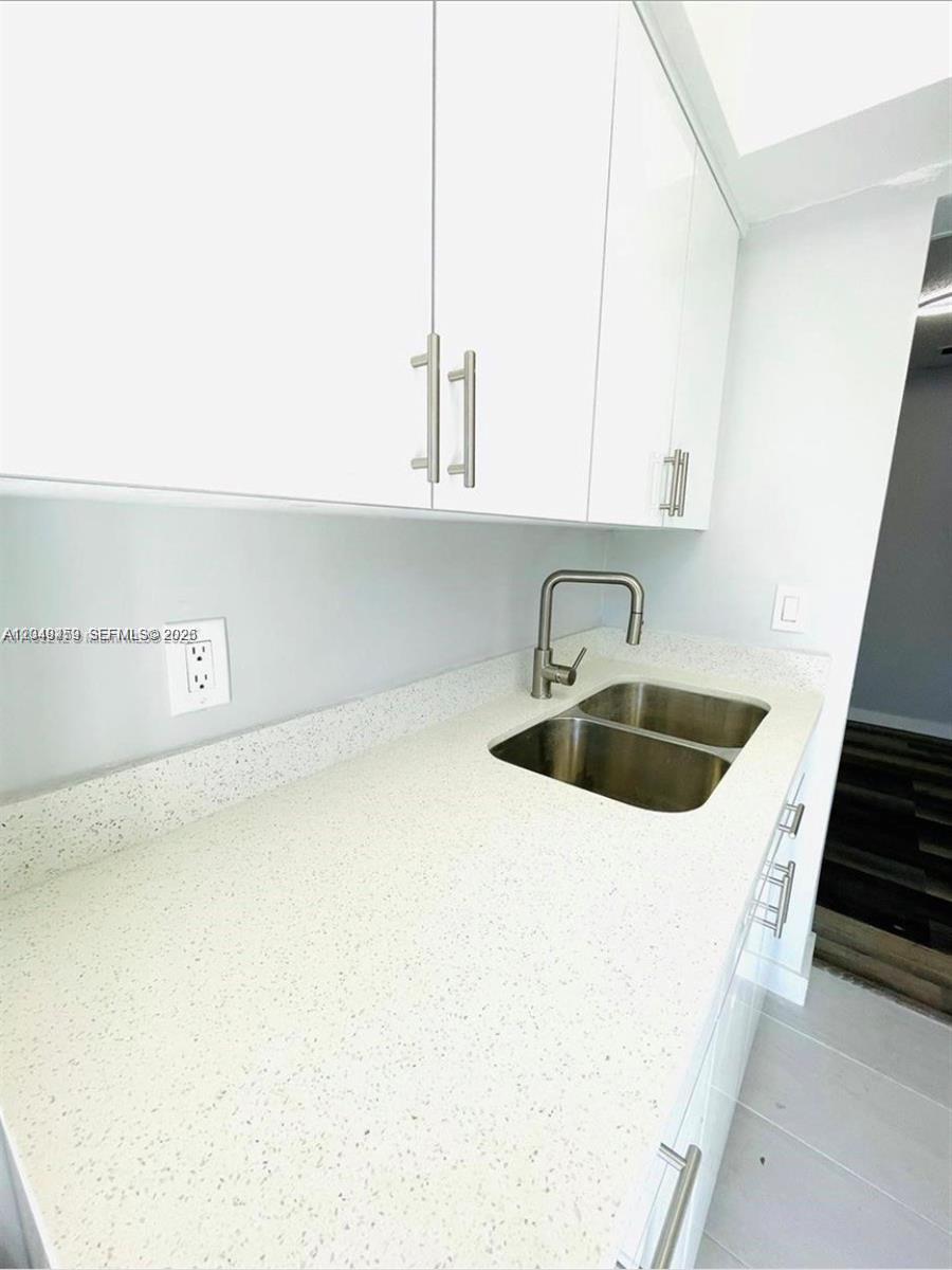 A kitchen features white cabinets, a speckled countertop, and a double-basin stainless steel sink — 1431 S 14th Ave # 208, Hollywood FL 33020, HOLLYWOOD, FL