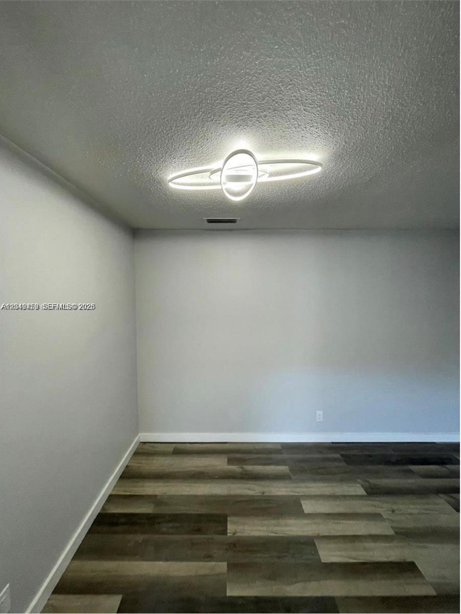 An empty room features light gray walls, a modern circular light fixture, and wood-look flooring — 1431 S 14th Ave # 208, Hollywood FL 33020, HOLLYWOOD, FL