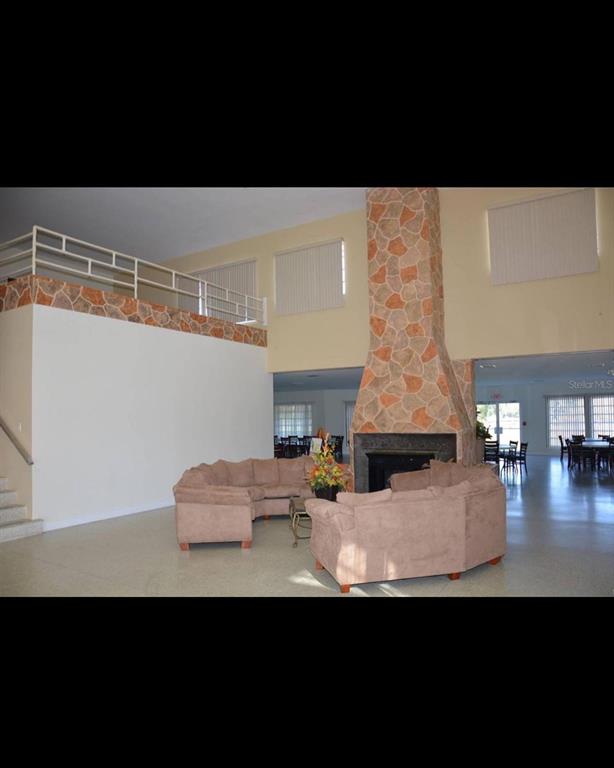 A spacious room features a large stone fireplace, a loft area, and beige sectional sofas — 1011 TROPICANA DRIVE, INDIAN LAKE ESTATES, FL