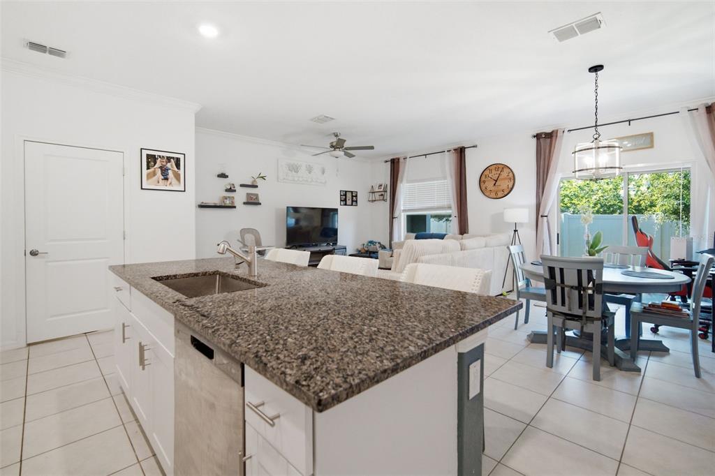 A kitchen island with a granite countertop and stainless steel sink overlooks an open living area — 21850 LYONIA LANE, LAND O LAKES, FL