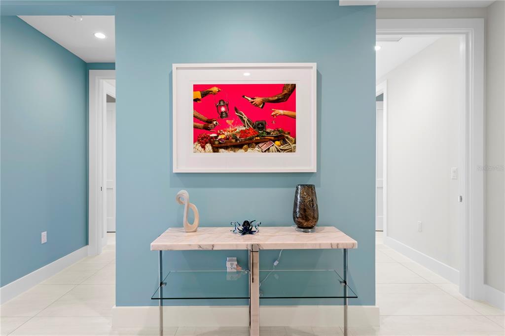 A console table with decor sits against a blue wall beneath a framed art piece — 275 1ST AVENUE S UNIT 3906, ST PETERSBURG, FL