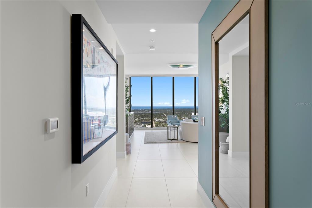 A hallway with a large framed print and mirror leads to a bright living area — 275 1ST AVENUE S UNIT 3906, ST PETERSBURG, FL