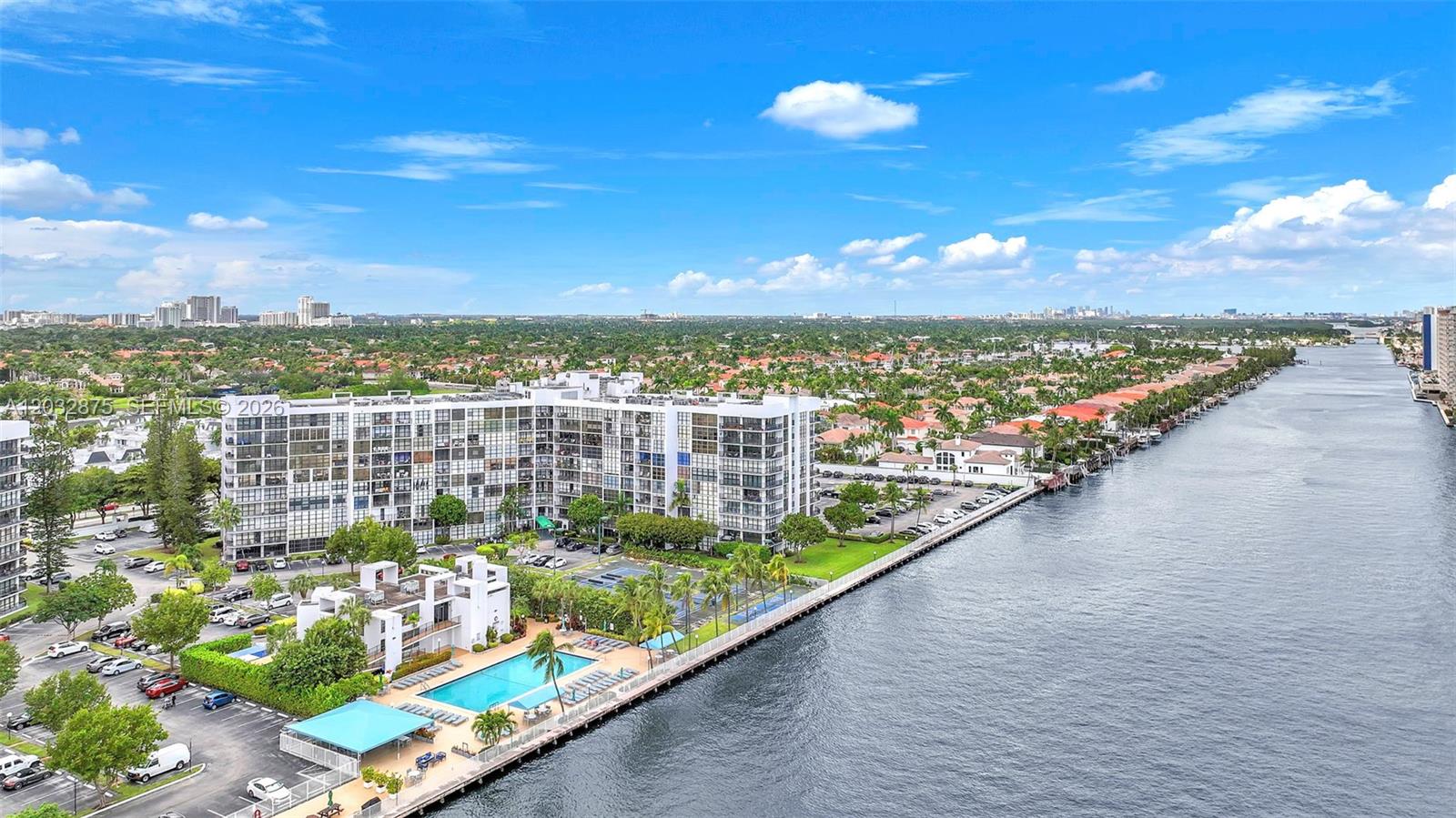 An aerial view shows a waterfront apartment complex with a pool and parking lot — 1000 Parkview Dr # 229, Hallandale Beach FL 33009, HALLANDALE BEACH, FL