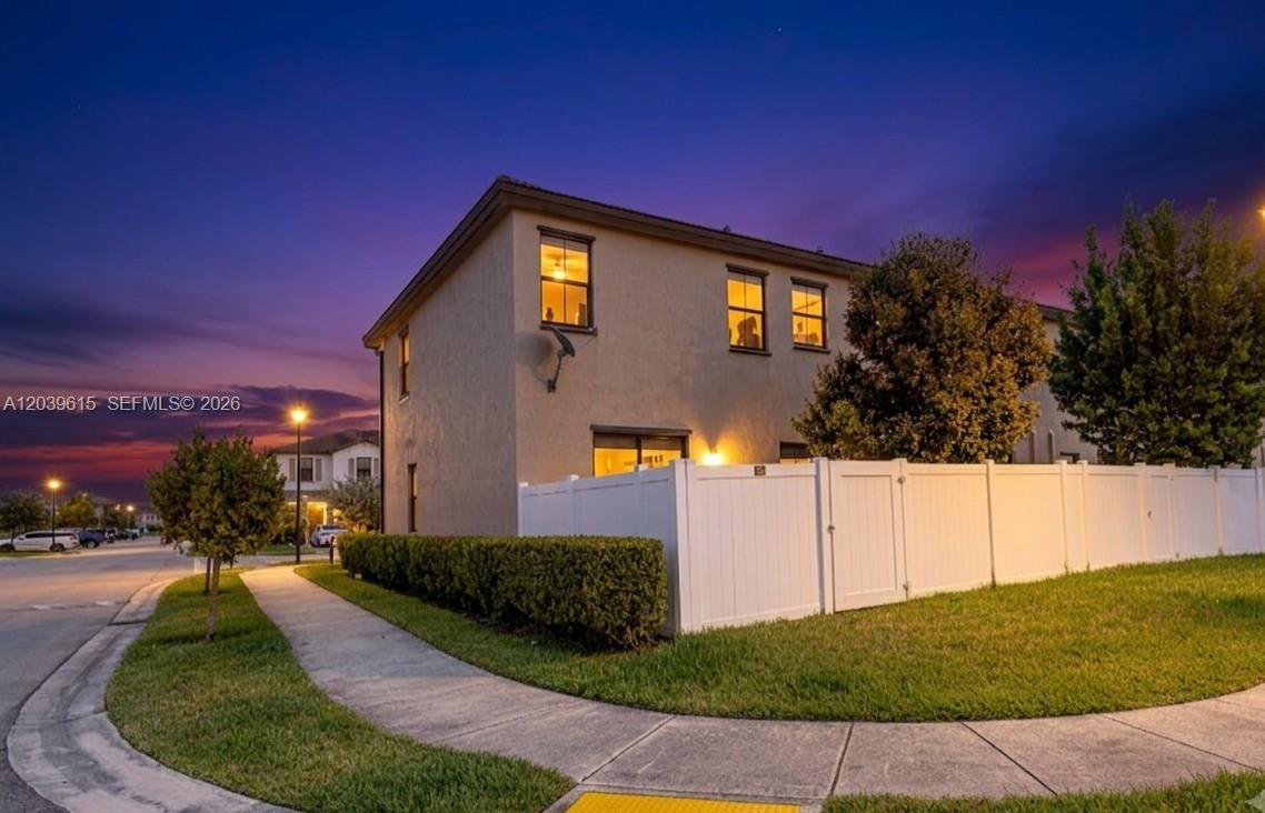 A two-story house exterior at dusk with a white fence and a sidewalk — 11064 W 33rd Way, Hialeah FL 33018, HIALEAH, FL