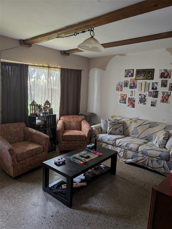 A living room features a sofa, two patterned armchairs, a coffee table, and exposed ceiling beams — 5610 WILSON ROAD, SANFORD, FL