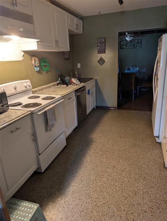 A kitchen features white cabinets, a white electric stove, a dishwasher, and speckled flooring — 5610 WILSON ROAD, SANFORD, FL