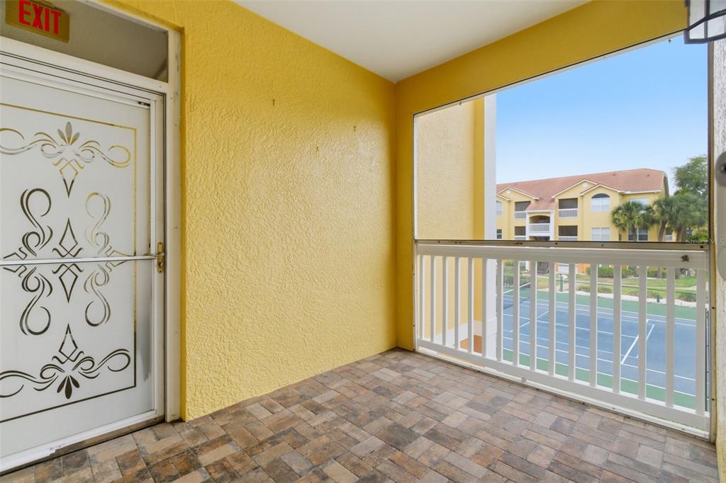 A covered balcony with yellow walls, a brown door, and a view of a tennis court — 10764 70TH AVENUE UNIT 6206, SEMINOLE, FL