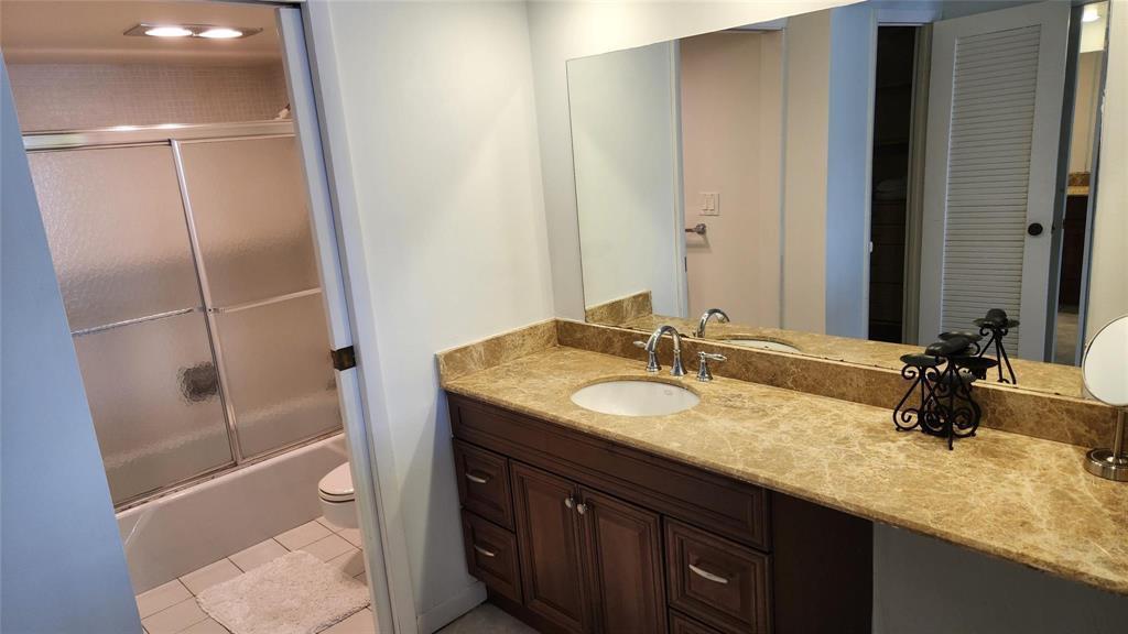 A bathroom features a dark wood vanity with a tan marble countertop and a shower-tub combo — 405 N Ocean Boulevard # 1507, Pompano Beach FL 33062, POMPANO BEACH, FL