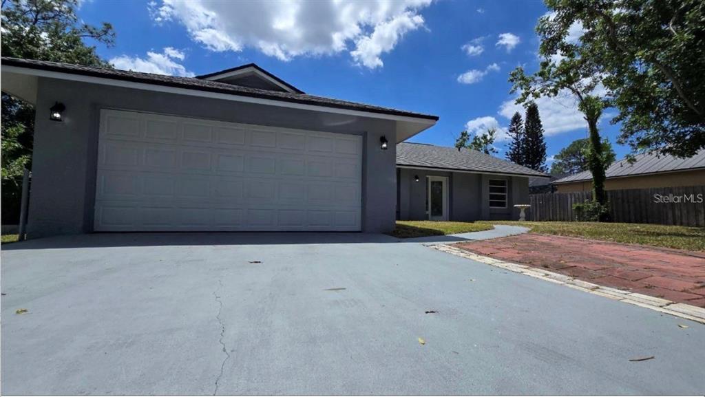 A gray single-story house features a two-car garage, a paved driveway, and a fenced yard — 34 EMERSON DRIVE NW, PALM BAY, FL