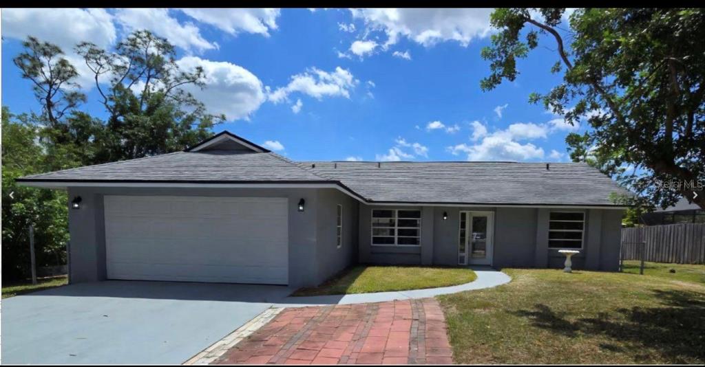 A gray single-story house with a two-car garage, a brick walkway, and a shingled roof — 34 EMERSON DRIVE NW, PALM BAY, FL