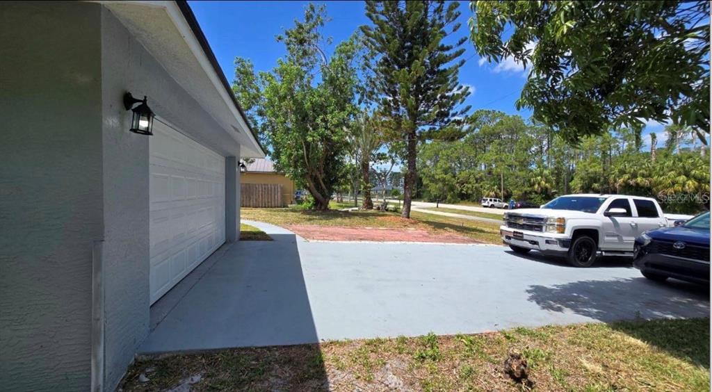 A gray house exterior features a white garage door, a concrete driveway, and parked vehicles — 34 EMERSON DRIVE NW, PALM BAY, FL