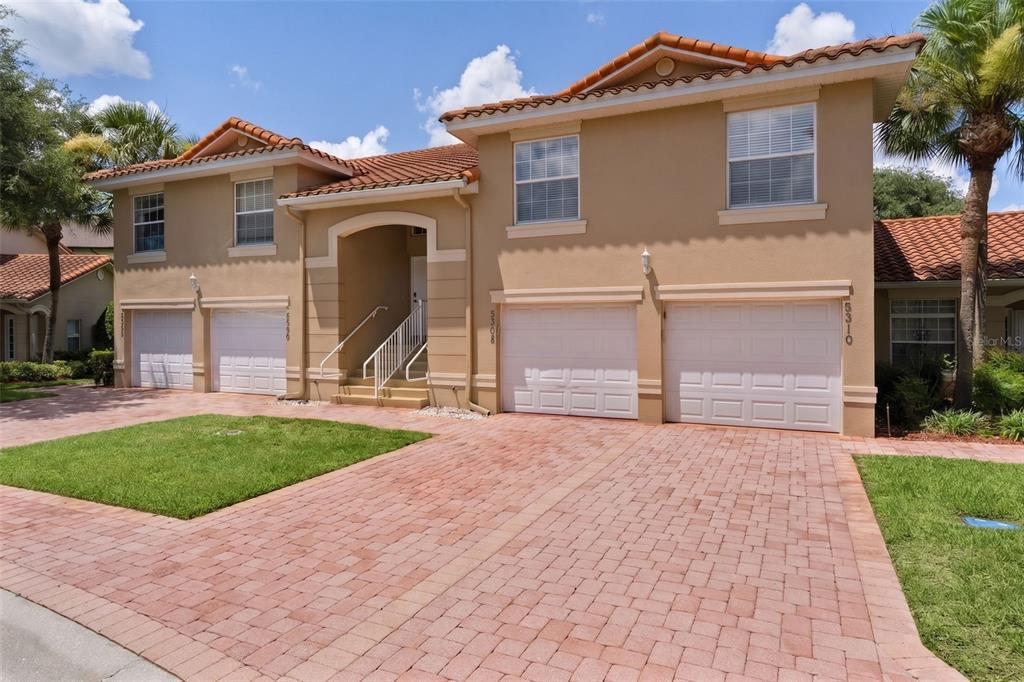 A two-story tan stucco house with a tile roof and four garage doors — 5308 BOWLINE COURT, OXFORD, FL