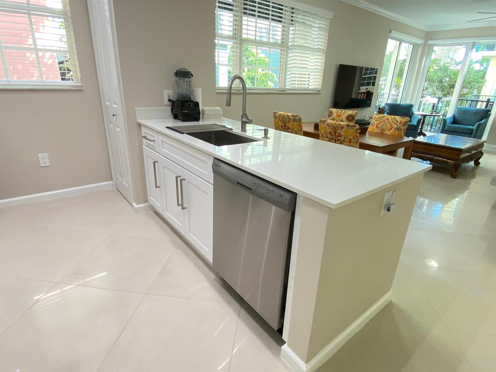 A kitchen island features white cabinets, a stainless steel dishwasher, and a white countertop — 225 NE 1st Street # 202, Delray Beach FL 33444, DELRAY BEACH, FL
