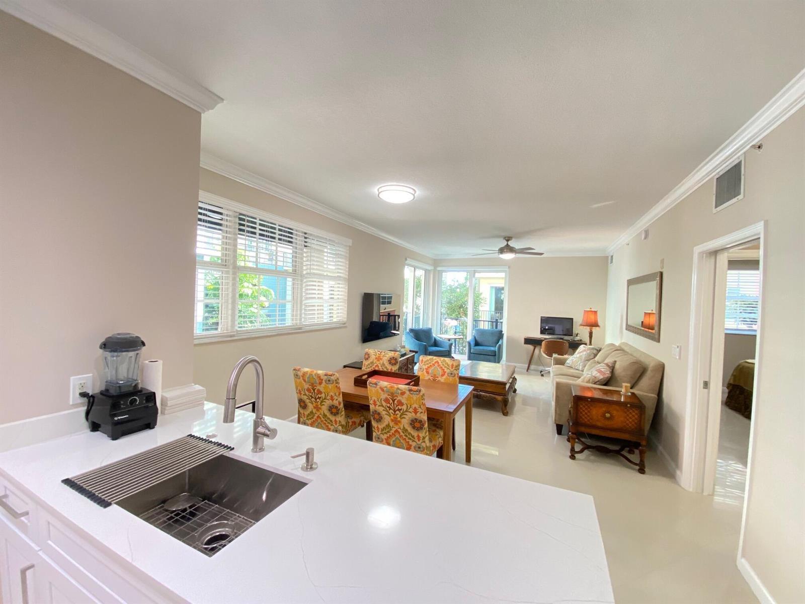 A kitchen island with a stainless steel sink overlooks an open-concept living and dining area — 225 NE 1st Street # 202, Delray Beach FL 33444, DELRAY BEACH, FL