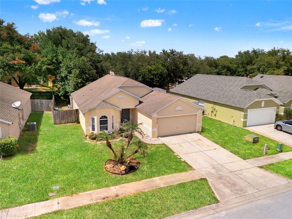 An aerial view of a single-story suburban house with a tan exterior and two-car garage — 2318 BARONS COURT, TAVARES, FL
